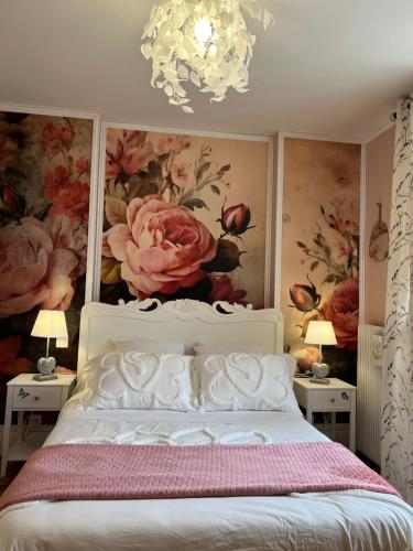 - une chambre avec un lit blanc et des fleurs sur le mur dans l'établissement La BOCQUILLONNE, à Purgerot