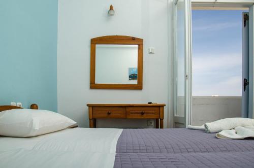 a bedroom with a bed and a mirror and a table at Hotel Livadia in Parikia