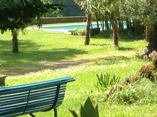 a park bench sitting in the grass next to a pool at La Rebière d'Or, B&B et Gîte in Mouleydier