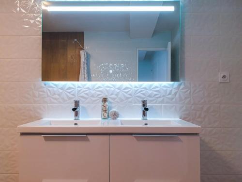une salle de bain avec un lavabo blanc et un miroir dans l'établissement Chez Tonton, à La Muraz