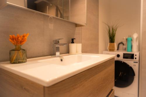 a bathroom with a sink with a vase of flowers at Appartement Cosy près de tout ! in Mons