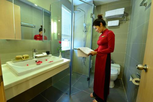 a woman in a bathroom with a sink and a shower at Hanoi Golden Sunshine Villa Hotel and Travel in Hanoi