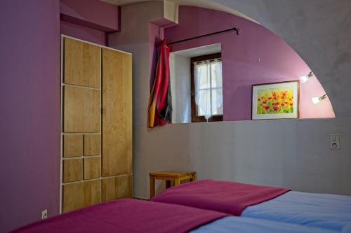 - une chambre avec des murs violets et un lit avec un miroir dans l'établissement La Vieille Tour, à Salavas