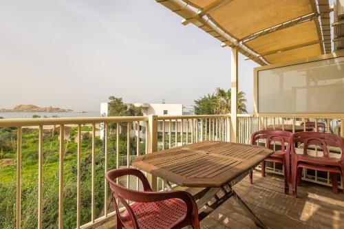 een houten tafel en stoelen op een terras met een scherm bij Le Rocher - Appt pour 6 climatisé avec piscine in LʼÎle-Rousse