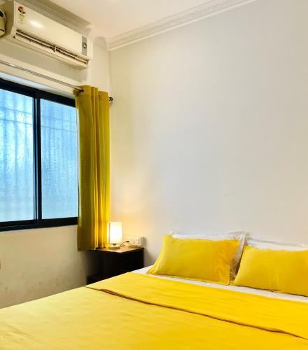 a bedroom with a yellow bed and a window at Aamra Ghar by evaddo in Mandrem