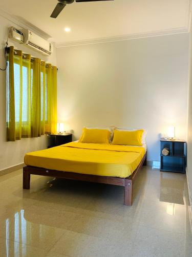 a bedroom with a large yellow bed with yellow pillows at Aamra Ghar by evaddo in Mandrem
