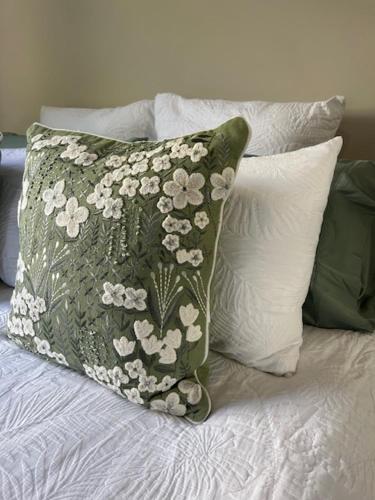 a green pillow with white flowers on a bed at Eton Cottage - Central Boutique Stay in Toowoomba