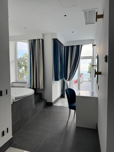 a bathroom with a tub and a desk and a chair at Positano Art Hotel Pasitea in Positano