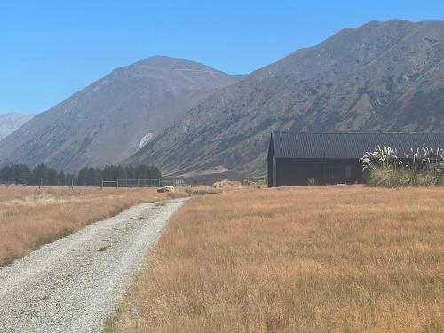 a barn in a field with mountains in the background at Ruakahu Lodge - Private Lodge in Ben Ohau - Twizel in Twizel