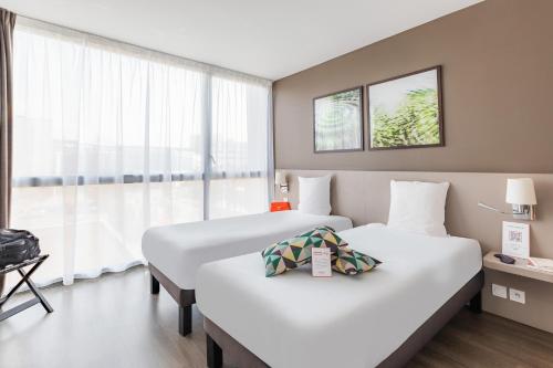 a hotel room with two beds and a window at Appart’City Confort Rennes – Cesson Sévigné in Cesson-Sévigné