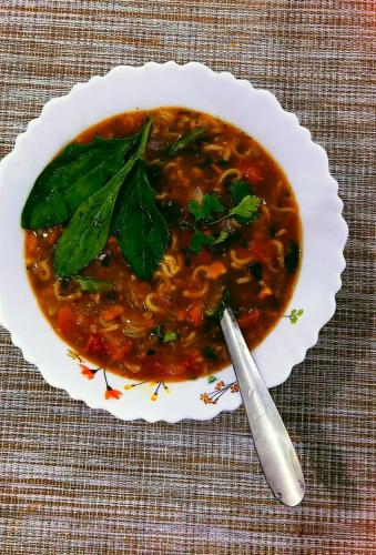 a bowl of soup with a spoon on a table at Hotel Himalayan in Madheso