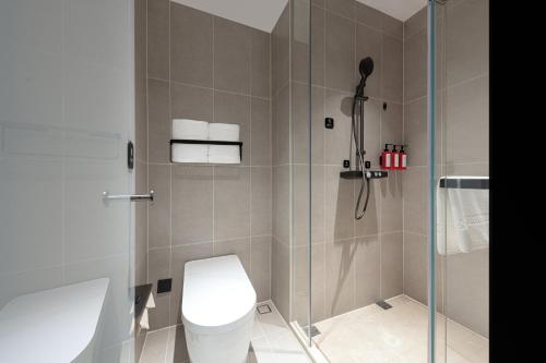 a bathroom with a toilet and a glass shower at Atour Light Hotel Wuhan Optics Valley Square Subway Station in Wuhan