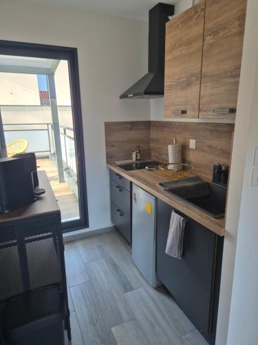 - une cuisine avec un évier et un comptoir avec une fenêtre dans l'établissement Appartement 1 chambre et terrasse, à Vienne