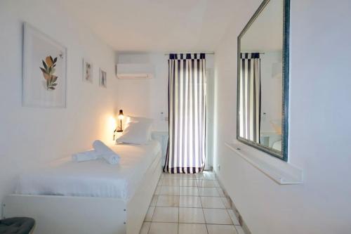une chambre blanche avec un lit et un miroir dans l'établissement Villa Este Family, 4 pers, parking, piscine, à Antibes