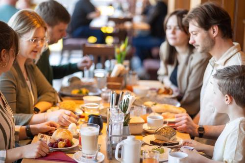Landgasthof Am Sonnenhang في فوهنشتراوس: مجموعة من الأشخاص يجلسون على طاولة ويتناولون الطعام