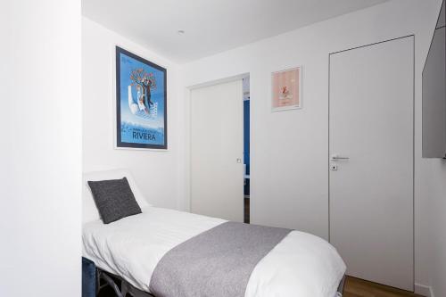a white bedroom with a bed and a picture on the wall at Sanremissimo Rooms & Apartment in Sanremo