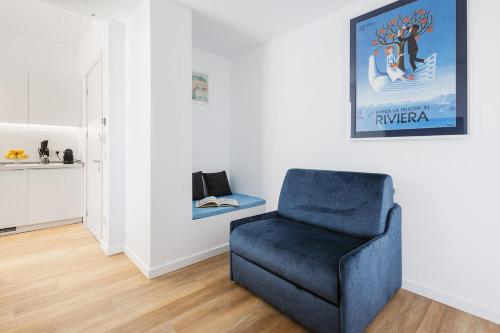 a blue chair in a white room with a picture at Sanremissimo Rooms & Apartment in Sanremo