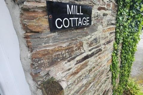 a sign on the side of a brick wall with ivy at The Mill House in Tintagel