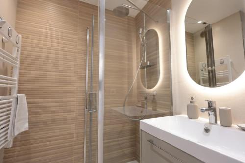 une salle de bain avec une douche, un lavabo et un miroir dans l'établissement Le Regina - Apt standing 2 Prs - Clim - Parking, à Antibes