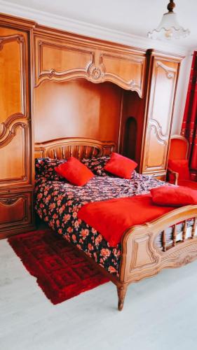 - une chambre avec un grand lit en bois et des oreillers rouges dans l'établissement COSY BIG HOUSE near Paris, Roissy, big parking, au Blanc-Mesnil