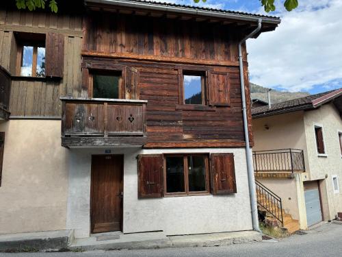 - un bâtiment avec des portes et des fenêtres en bois sur une rue dans l'établissement Les 4 maisons Brides-les-Bains, à Brides-les-Bains