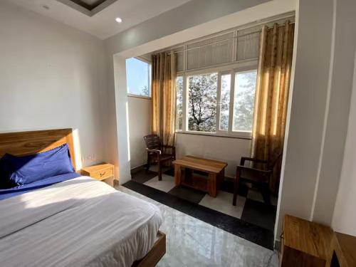 a bedroom with a bed and a window and chairs at Nona shona chill point homestay and cafe in Mussoorie
