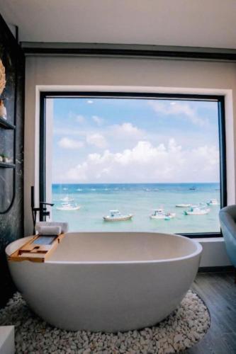 a large bath tub in a room with a large window at New Moon Hotel Phu Quy in Cu Lao Thu