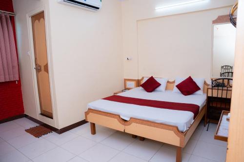 a bedroom with a bed with red pillows at SAIGAL Guest House in Mumbai