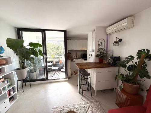 un salon avec une cuisine et un comptoir avec des plantes dans l'établissement Charmant T2 La Grande Motte Ponant - Draps, Clim, Wifi & Terrasse, à La Grande Motte