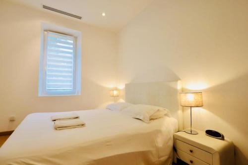 une chambre blanche avec un lit et une fenêtre dans l'établissement Les Muguets - Apt Standing 4 Prs - clim, parking, à Vallauris