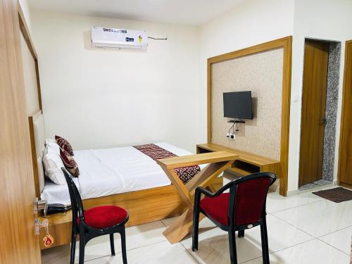 a room with a bed and two chairs and a tv at Hotel The Aadimata & Banquets in Chittaurgarh