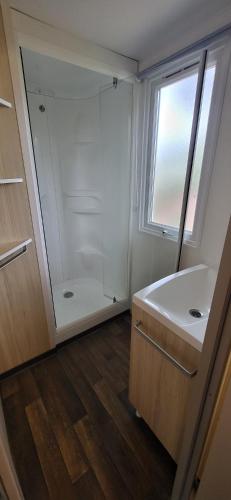 une salle de bain avec un lavabo et une douche en verre dans l'établissement Location Mobil home, à Torreilles