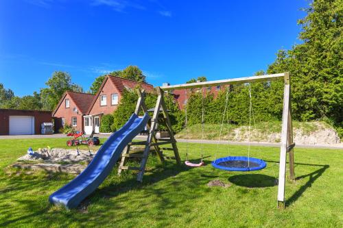 ein Spielplatz mit Rutsche und Schaukeln in einem Hof in der Unterkunft Ferienwohnungen und Ferienhaus Polmann in Nordwerdum in Werdum
