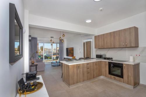 a kitchen with wooden cabinets and a living room at City Hall Suites in Limassol