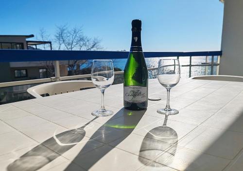 une bouteille de vin et deux verres à vin sur une table dans l'établissement Très belle T2, vue mer ,Le Tout a Pied, à Saint-Raphaël