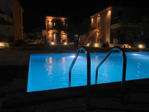 a swimming pool lit up at night with lights at Three Charites Resort in Gialova