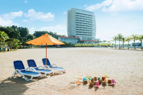 two chairs and an umbrella on a beach at Lexis Hibiscus Port Dickson in Port Dickson