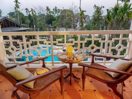a balcony with a table and chairs and a pool at Ancient Huế Garden Houses in Hue