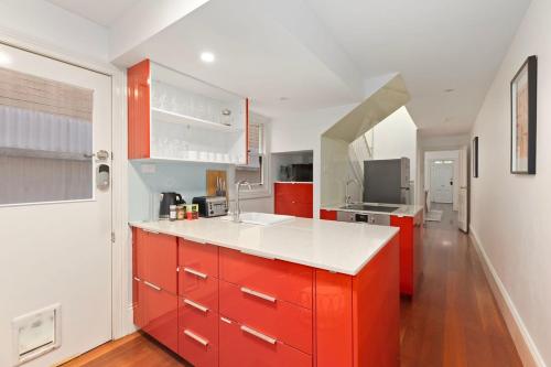 a kitchen with red cabinets and a white counter top at Holiday Home with Outdoor Area for 8 Guests in Sydney