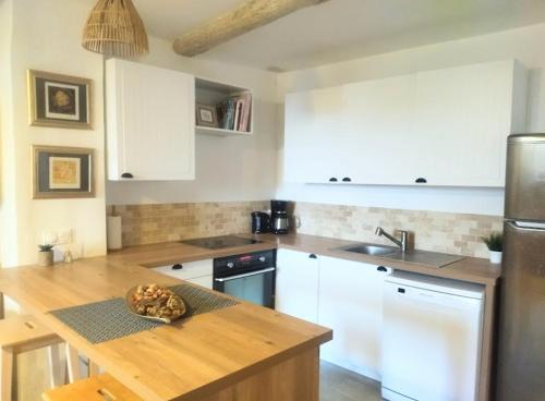 une cuisine avec des armoires blanches et un comptoir en bois dans l'établissement Charmant appartement au cœur du village de Fayence, à Fayence