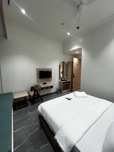 a bedroom with a large white bed and a television at Hotel The Octave in Surat