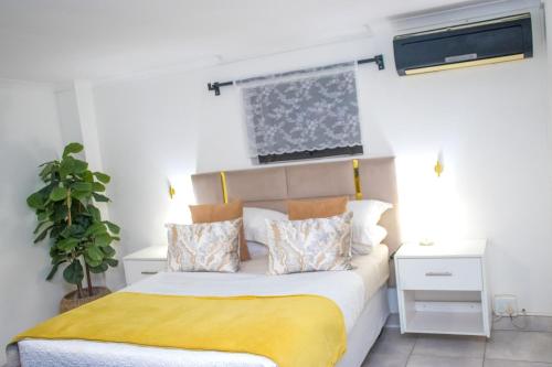 a bedroom with a bed with a yellow blanket on it at Optimum Stay Self Catering Accommodation - Deluxe Room in Cape Town