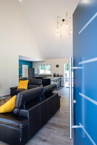 un salon avec un canapé en cuir noir dans l'établissement Gîte la Seigneurie -Piscine & SPA, à Saumur