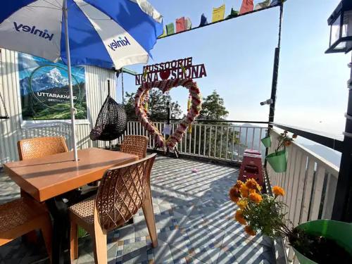 a deck with a table and chairs and an umbrella at Nona shona chill point homestay and cafe in Mussoorie