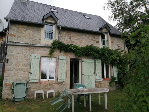 une maison en pierre avec une table en face dans l'établissement Charmante petite maison proche de Meymac, à Meymac