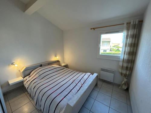 Lyo pavillon في فالراس بلاج: غرفة نوم صغيرة بها سرير ونافذة