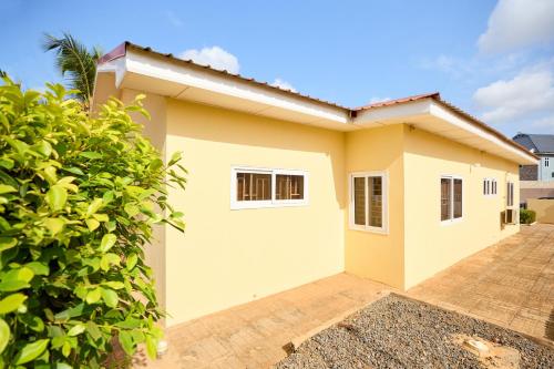 a yellow house with a fence in front of it at Groove Lodge in Tema