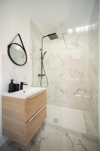 une salle de bain avec un lavabo et une douche avec un miroir dans l'établissement Appartement climatisé 2 chambres avec parking à 10min à pieds de la Gare St Charles, à Marseille