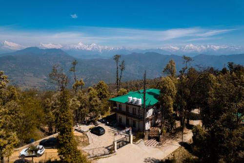 an aerial view of a house with mountains in the background at THE HIMALAYAN WOODS, CHAUKORI in Chaukori