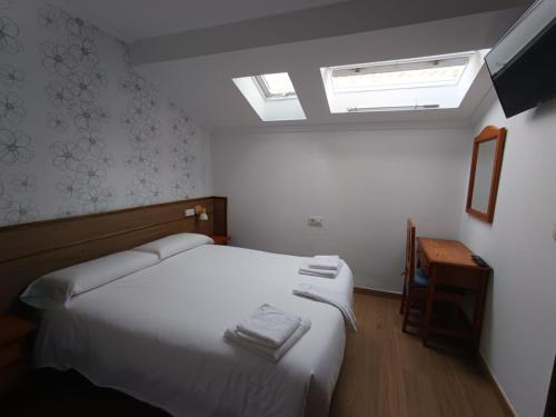 a small bedroom with a bed and a skylight at Pensión O Escondidino in Baiona